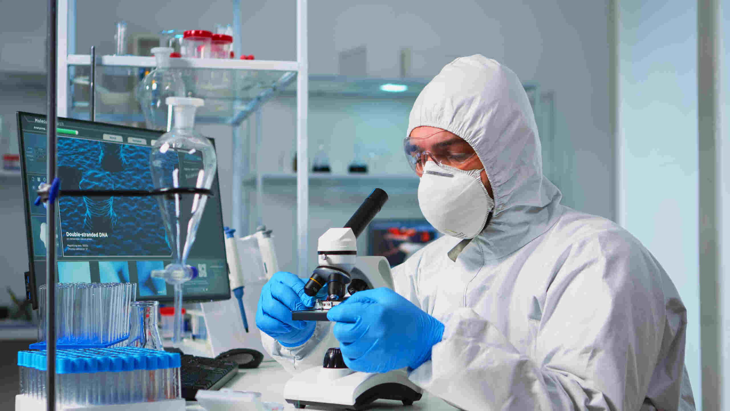 scientist-ppe-suit-placing-slide-specimen-stage-laboratory-microscope-making-adjustments-chemist-coverall-working-with-various-bacteria-tissue-blood-samples-antibiotics-research-scaled